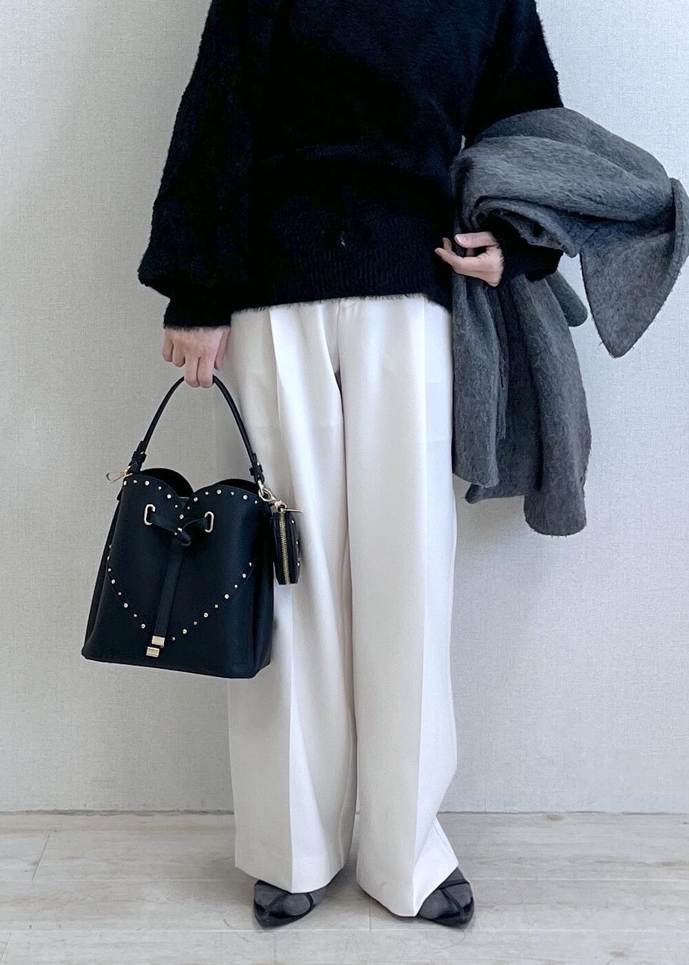 グレー系のブルゾン、ホワイト系のスラックス、ブラック系のニット/セーターを着用したレディースの冬コーディネートの8枚目の写真