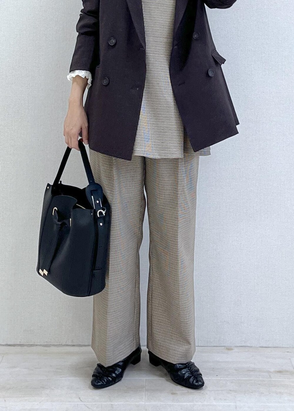 ベージュ系のスラックス、ブラウン系のテーラードジャケット、ベージュ系のキャミソールを着用したレディースの秋コーディネートの2枚目の写真