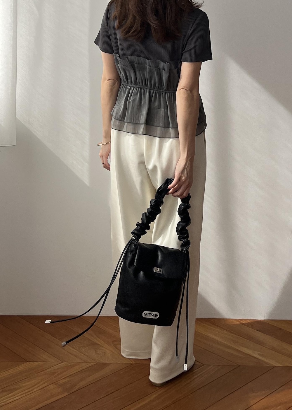 ホワイト系のスラックス、ブラック系のショルダーバッグ、ホワイト系のサンダルを着用したレディースの春コーディネートの5枚目の写真