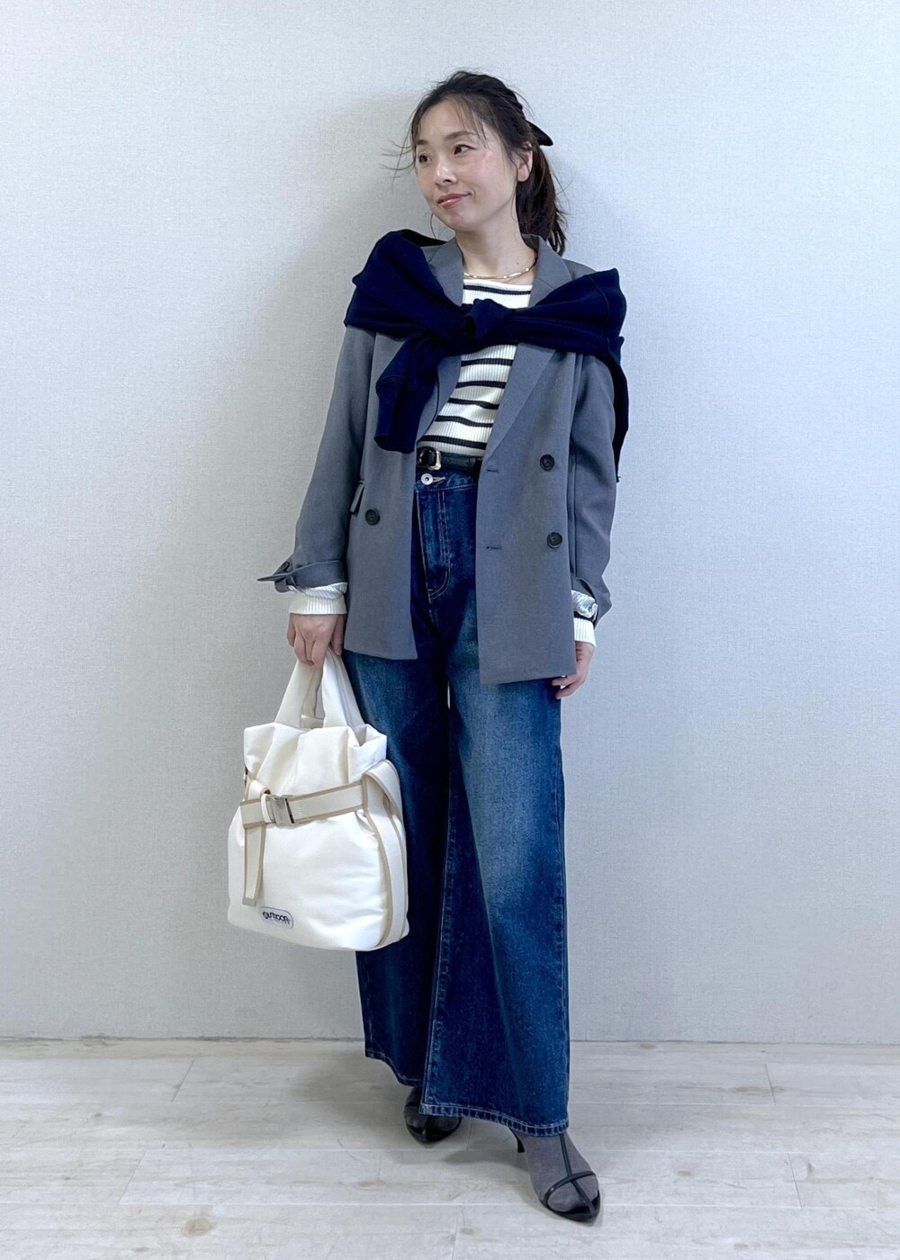 グレー系のテーラードジャケット、ブルー系のデニムパンツ、ホワイト系のニット/セーターを着用したレディースの冬コーディネートの9枚目の写真