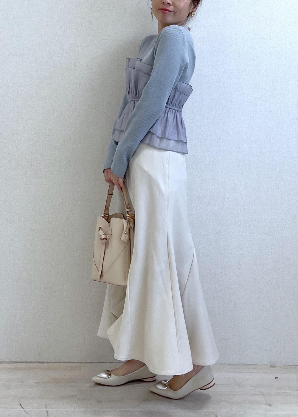 ベージュ系のショルダーバッグ、ホワイト系のバレエシューズ、ブルー系のニット/セーターを着用したレディースの春コーディネートの2枚目の写真