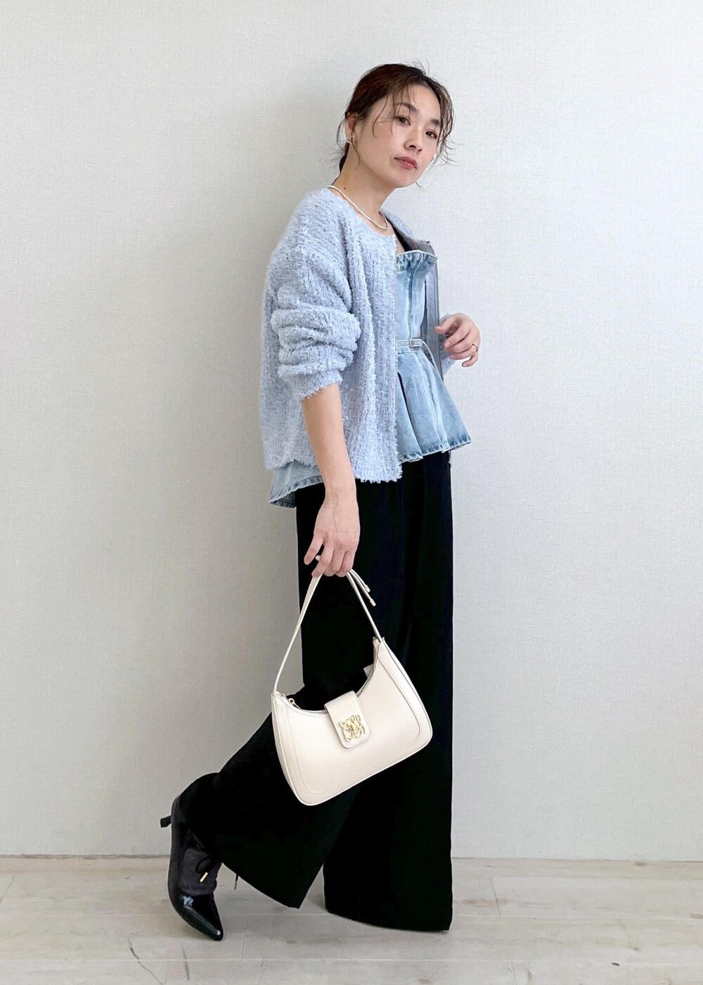 ホワイト系のハンドバッグ、ブルー系のカーディガン/ボレロ、ブラック系のサロペット/オーバーオールを着用したレディースの春コーディネートの2枚目の写真