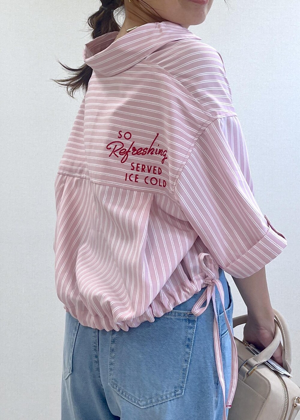 ブラック系のサンダル、ブルー系のデニムパンツ、ベージュ系のボストンバッグを着用したレディースの夏コーディネートの6枚目の写真