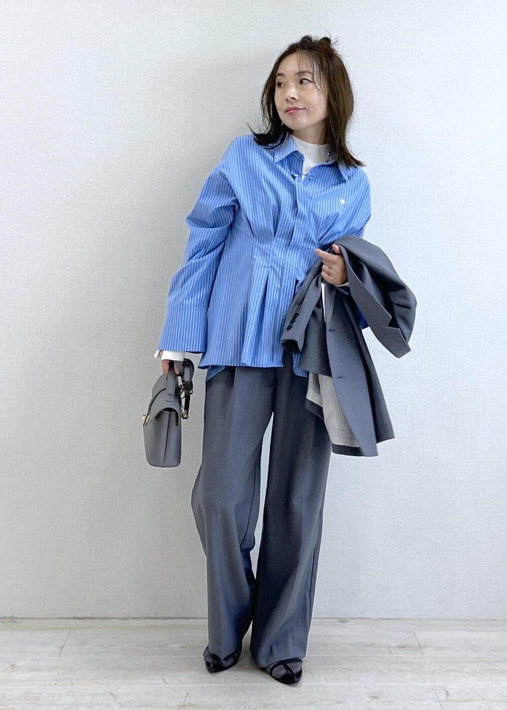 グレー系のショルダーバッグ、ブルー系のシャツ/ブラウス、ホワイト系のニット/セーターを着用したレディースの秋コーディネートの5枚目の写真