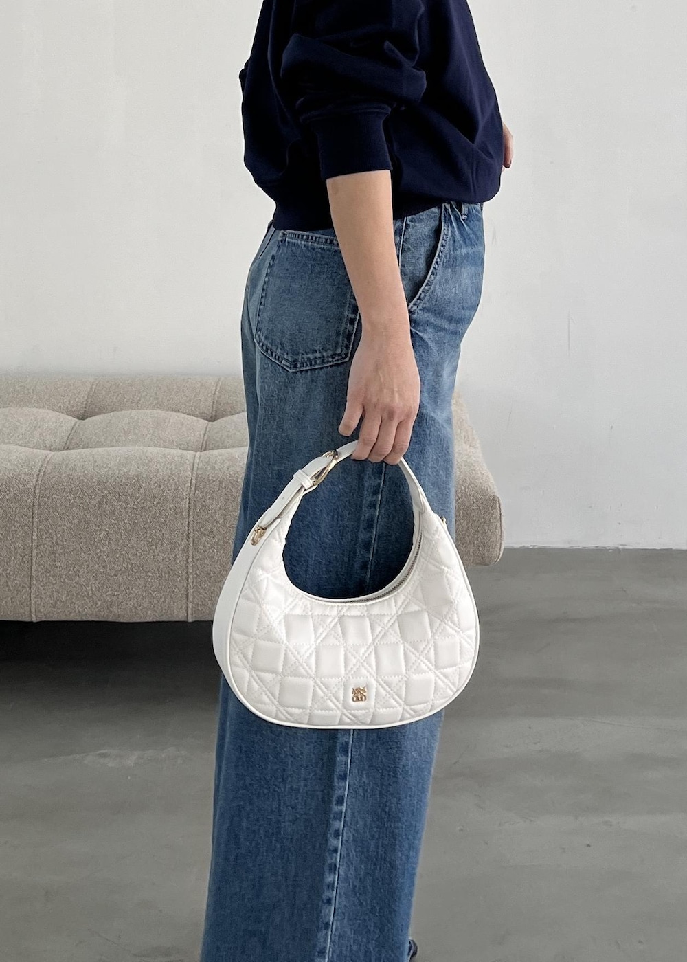 ホワイト系のハンドバッグ、ブラック系のパンプス、ブルー系のデニムパンツを着用したレディースの冬コーディネートの9枚目の写真