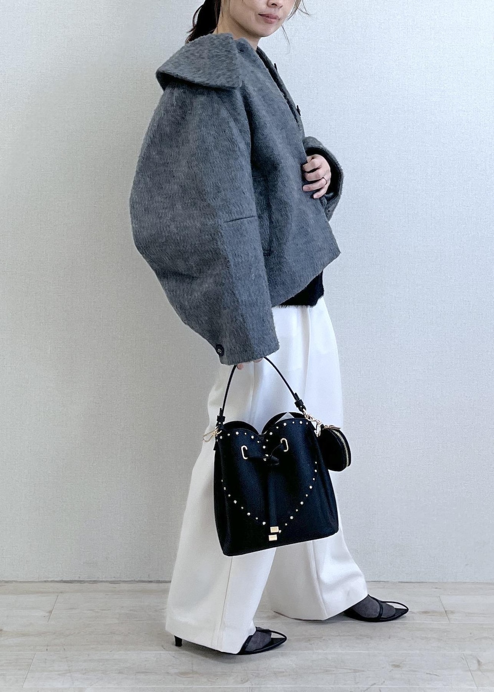 グレー系のブルゾン、ホワイト系のスラックス、ブラック系のニット/セーターを着用したレディースの冬コーディネートの3枚目の写真