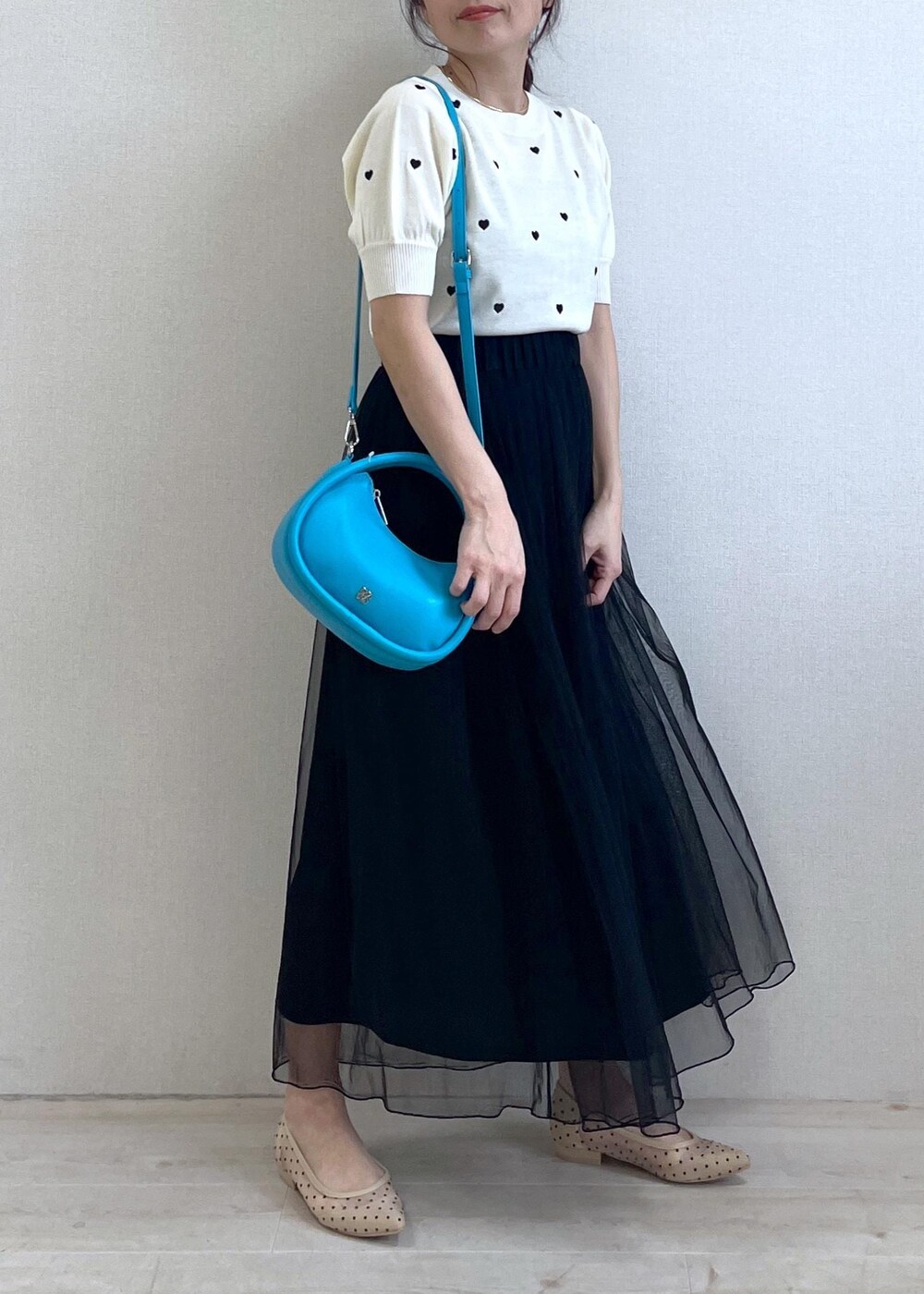 ベージュ系のパンプス、ブラック系のスカート、ホワイト系のニット/セーターを着用したレディースの春コーディネートの2枚目の写真