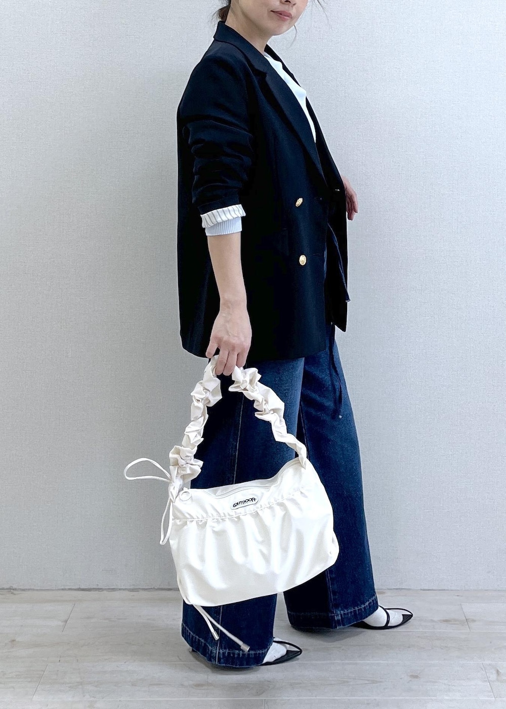 ブルー系のテーラードジャケット、ブルー系のデニムパンツ、ホワイト系のショルダーバッグを着用したレディースの冬コーディネートの3枚目の写真