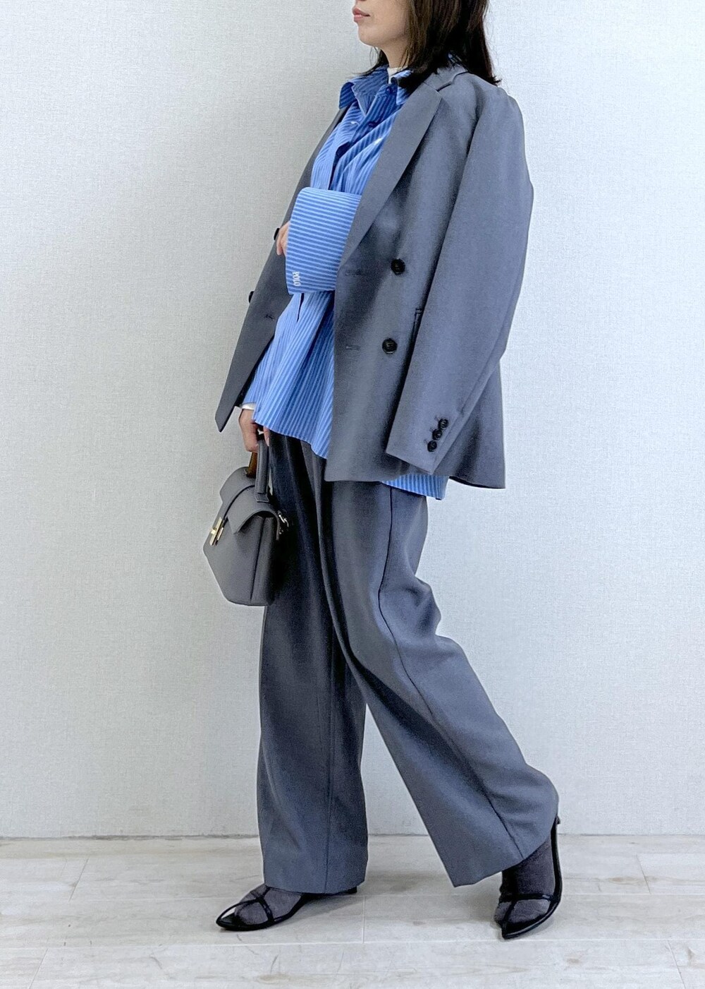 グレー系のショルダーバッグ、ブルー系のシャツ/ブラウス、ホワイト系のニット/セーターを着用したレディースの秋コーディネートの2枚目の写真