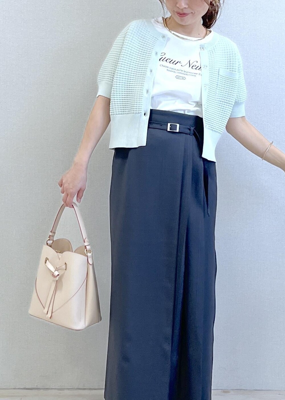 ベージュ系のショルダーバッグ、ホワイト系のTシャツ/カットソー、グレー系のスカートを着用したレディースの春コーディネートの6枚目の写真