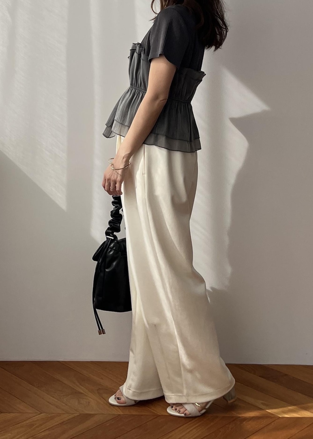ホワイト系のスラックス、ブラック系のショルダーバッグ、ホワイト系のサンダルを着用したレディースの春コーディネートの4枚目の写真