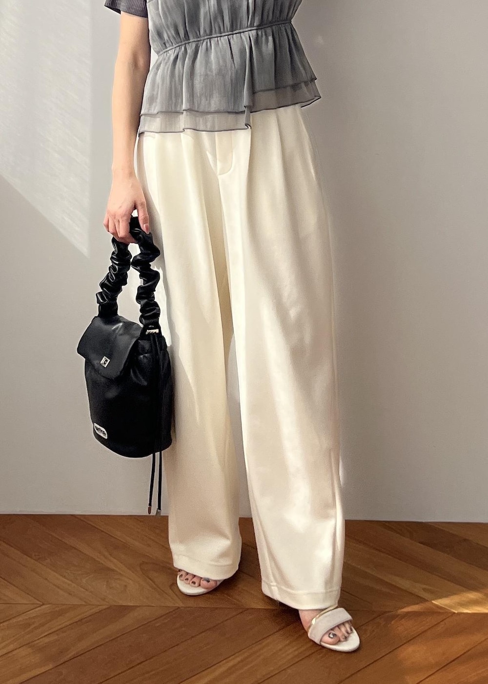 ホワイト系のスラックス、ブラック系のショルダーバッグ、ホワイト系のサンダルを着用したレディースの春コーディネートの7枚目の写真