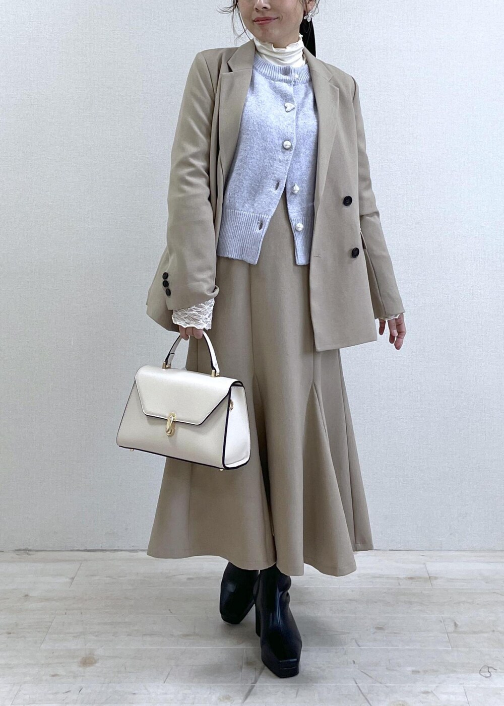 ブラック系のブーツ、ベージュ系のスカート、パープル系のカーディガン/ボレロを着用したレディースの秋コーディネートの10枚目の写真
