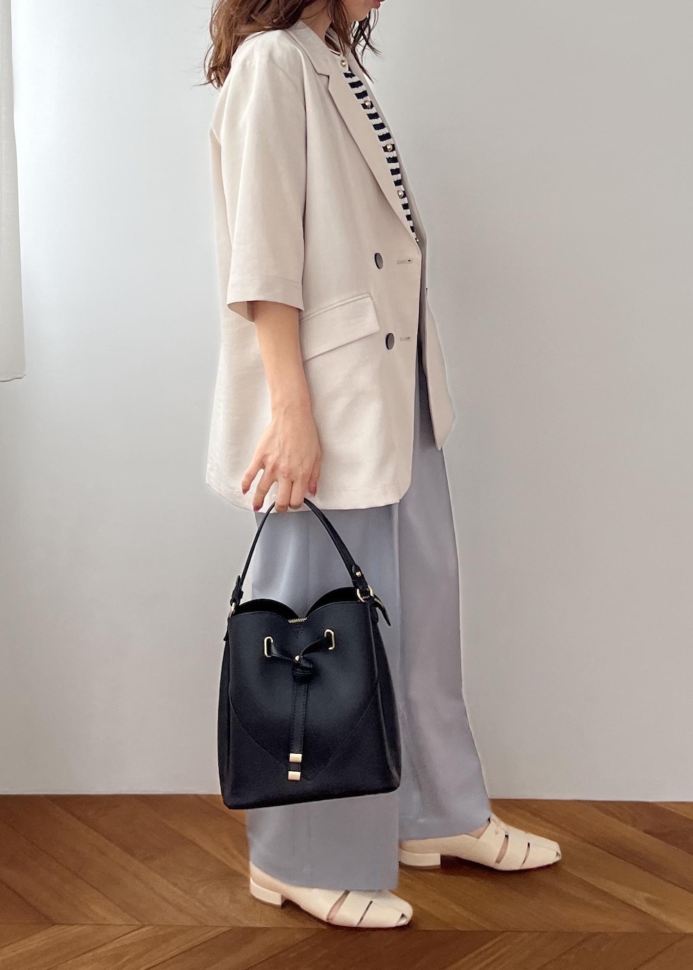 ブラック系のショルダーバッグ、ホワイト系のパンプス、ブルー系のその他パンツを着用したレディースの春コーディネートの3枚目の写真