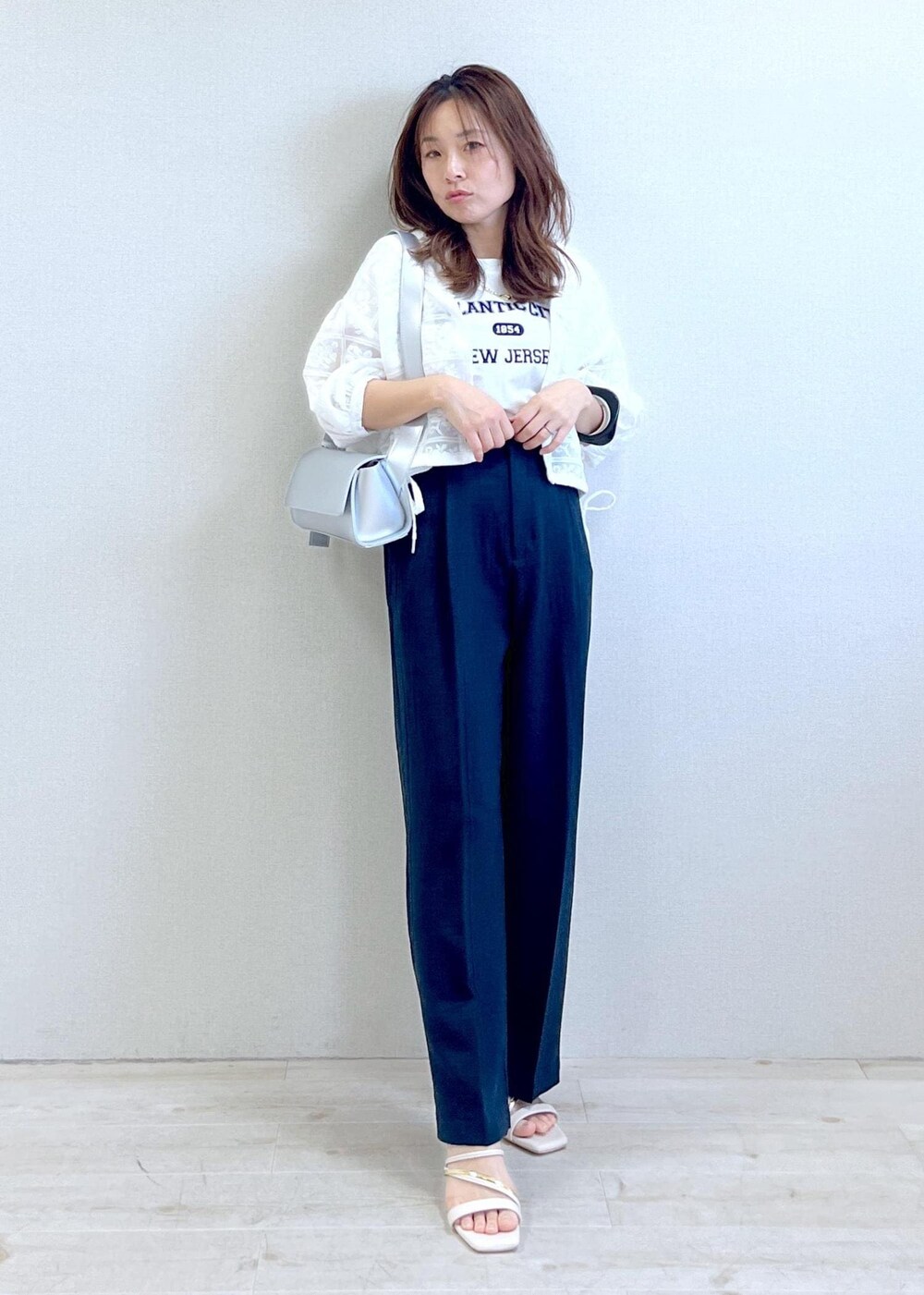 シルバー系のショルダーバッグ、ホワイト系のTシャツ/カットソー、ホワイト系のサンダルを着用したレディースの春コーディネートの2枚目の写真