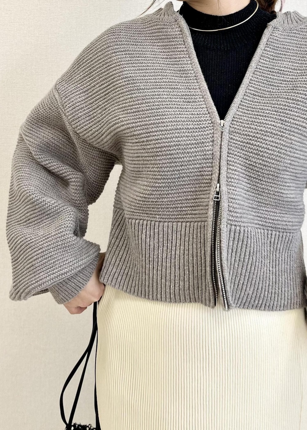 ホワイト系のスカート、ブラック系のニット/セーター、シルバー系のハンドバッグを着用したレディースの冬コーディネートの4枚目の写真