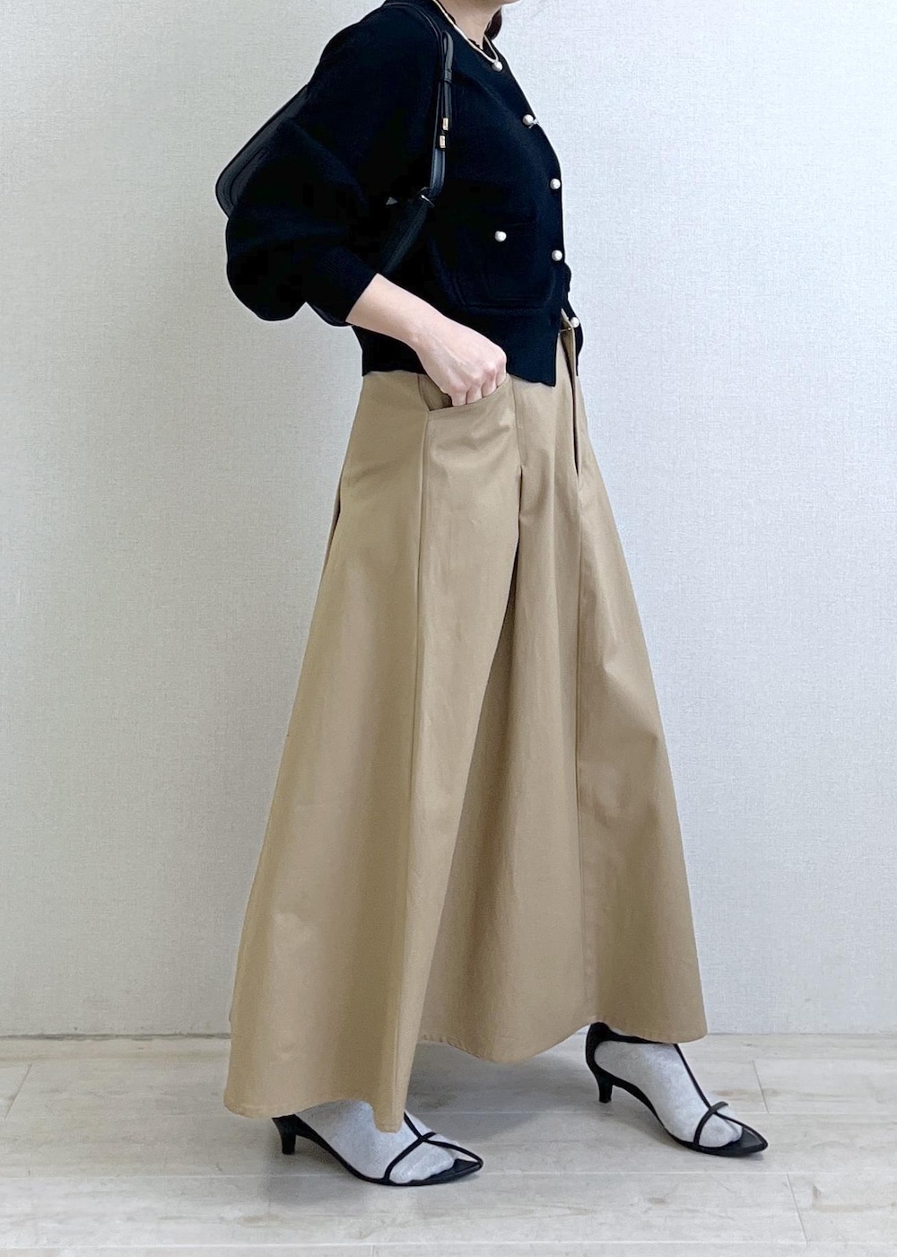 ブラック系のショルダーバッグ、ブラック系のカーディガン/ボレロ、ベージュ系のスカートを着用したレディースの春コーディネートの4枚目の写真