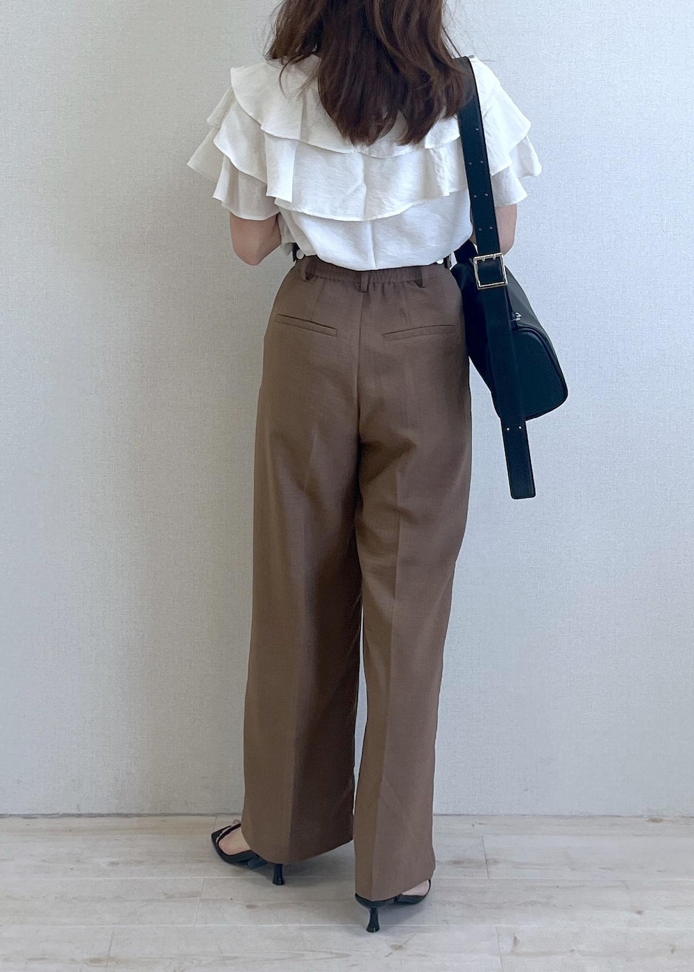 ブラック系のショルダーバッグ、ブラック系のサンダル、ブラウン系のスラックスを着用したレディースの夏コーディネートの4枚目の写真