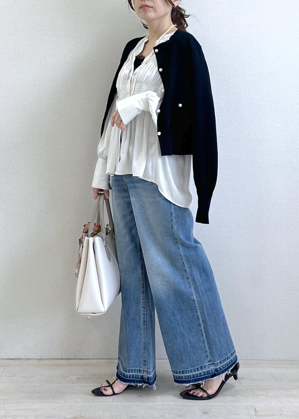 ブラック系のキャミソール、ブルー系のデニムパンツ、ブラック系のカーディガン/ボレロを着用したレディースの春コーディネートの3枚目の写真