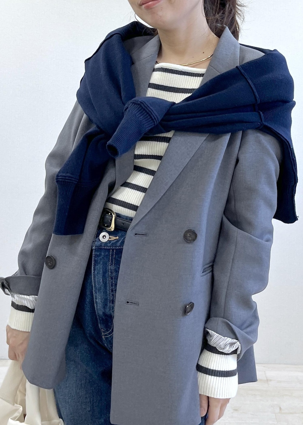 グレー系のテーラードジャケット、ブルー系のデニムパンツ、ホワイト系のニット/セーターを着用したレディースの冬コーディネートの8枚目の写真