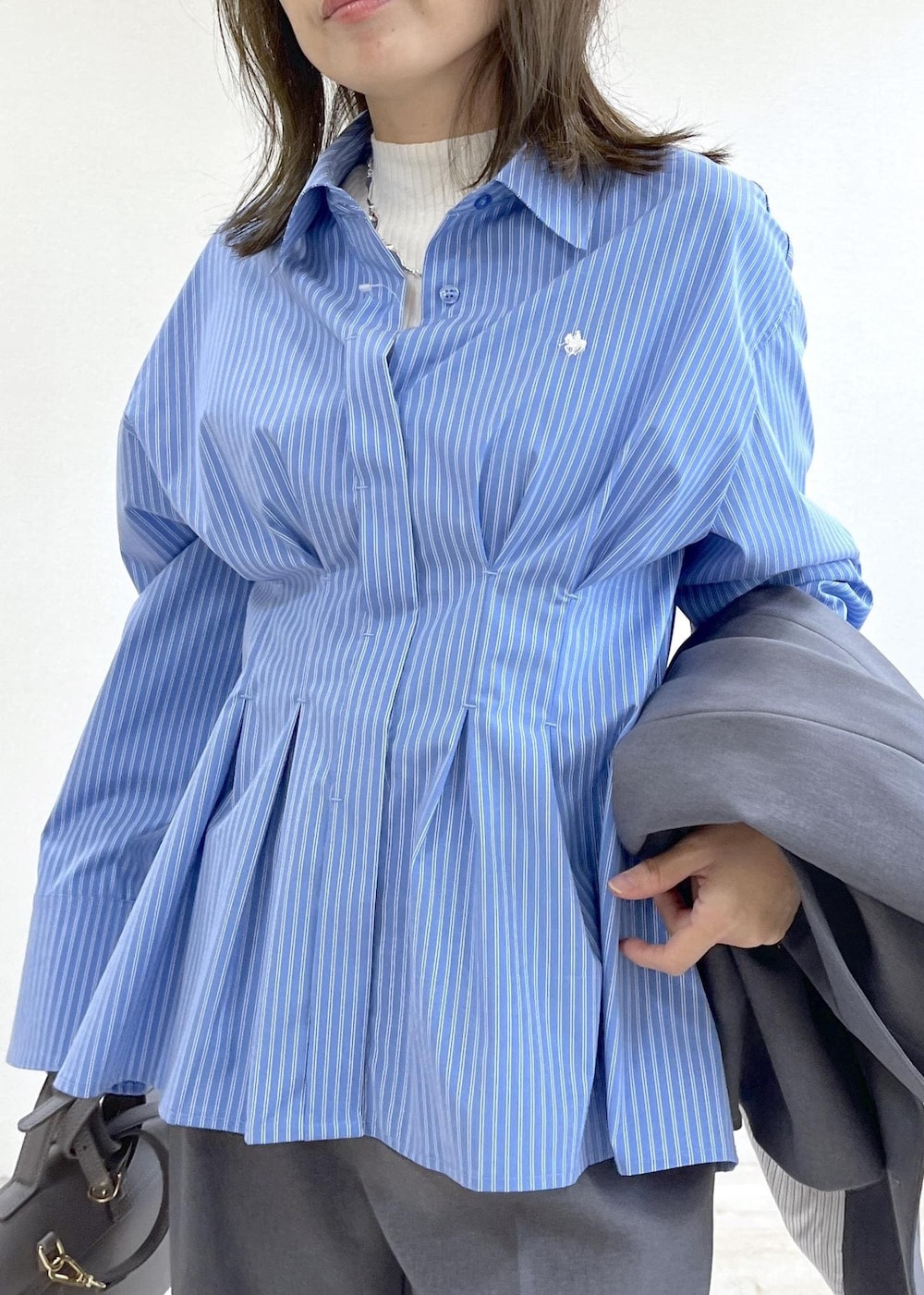 グレー系のショルダーバッグ、ブルー系のシャツ/ブラウス、ホワイト系のニット/セーターを着用したレディースの秋コーディネートの8枚目の写真