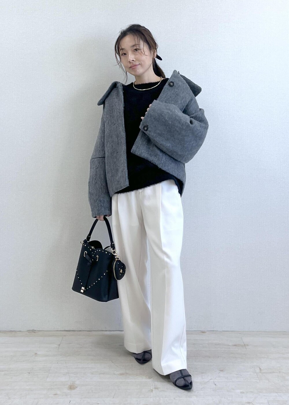 グレー系のブルゾン、ホワイト系のスラックス、ブラック系のニット/セーターを着用したレディースの冬コーディネートの10枚目の写真