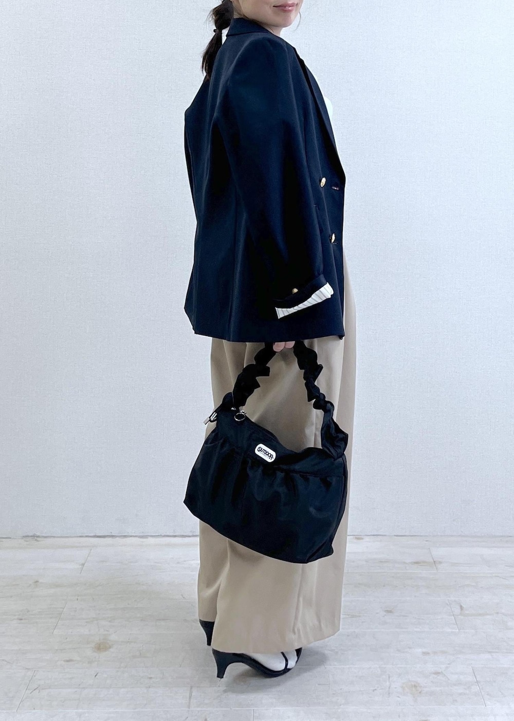 ブルー系のテーラードジャケット、ベージュ系のその他パンツ、ブラック系のショルダーバッグを着用したレディースの冬コーディネートの2枚目の写真