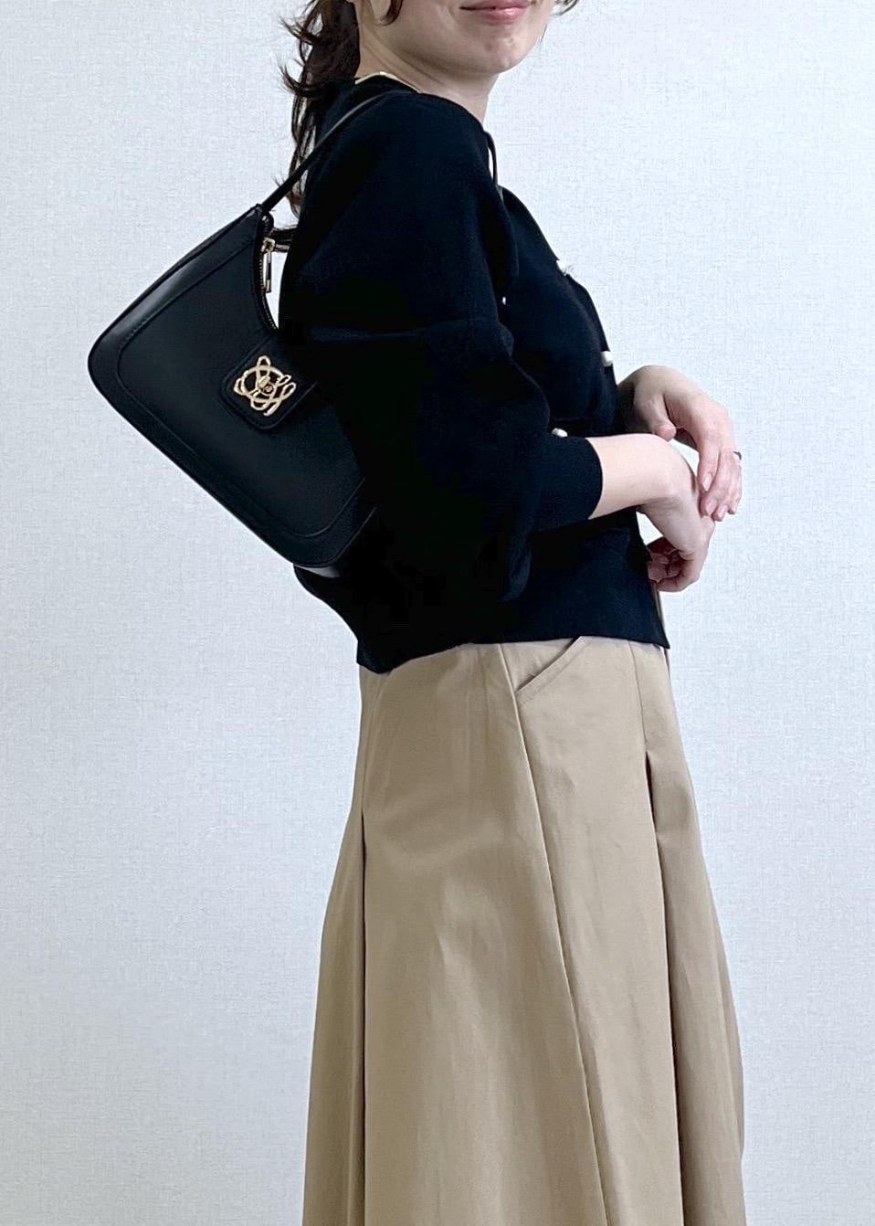 ブラック系のショルダーバッグ、ブラック系のカーディガン/ボレロ、ベージュ系のスカートを着用したレディースの春コーディネートの3枚目の写真