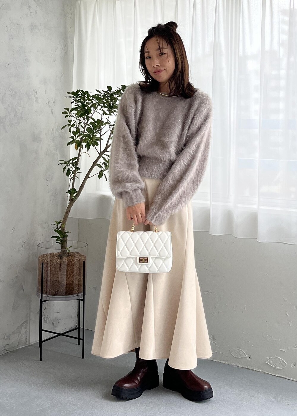 ブラウン系のブーツ、ホワイト系のスカート、ベージュ系のニット/セーターを着用したレディースの秋コーディネートの7枚目の写真