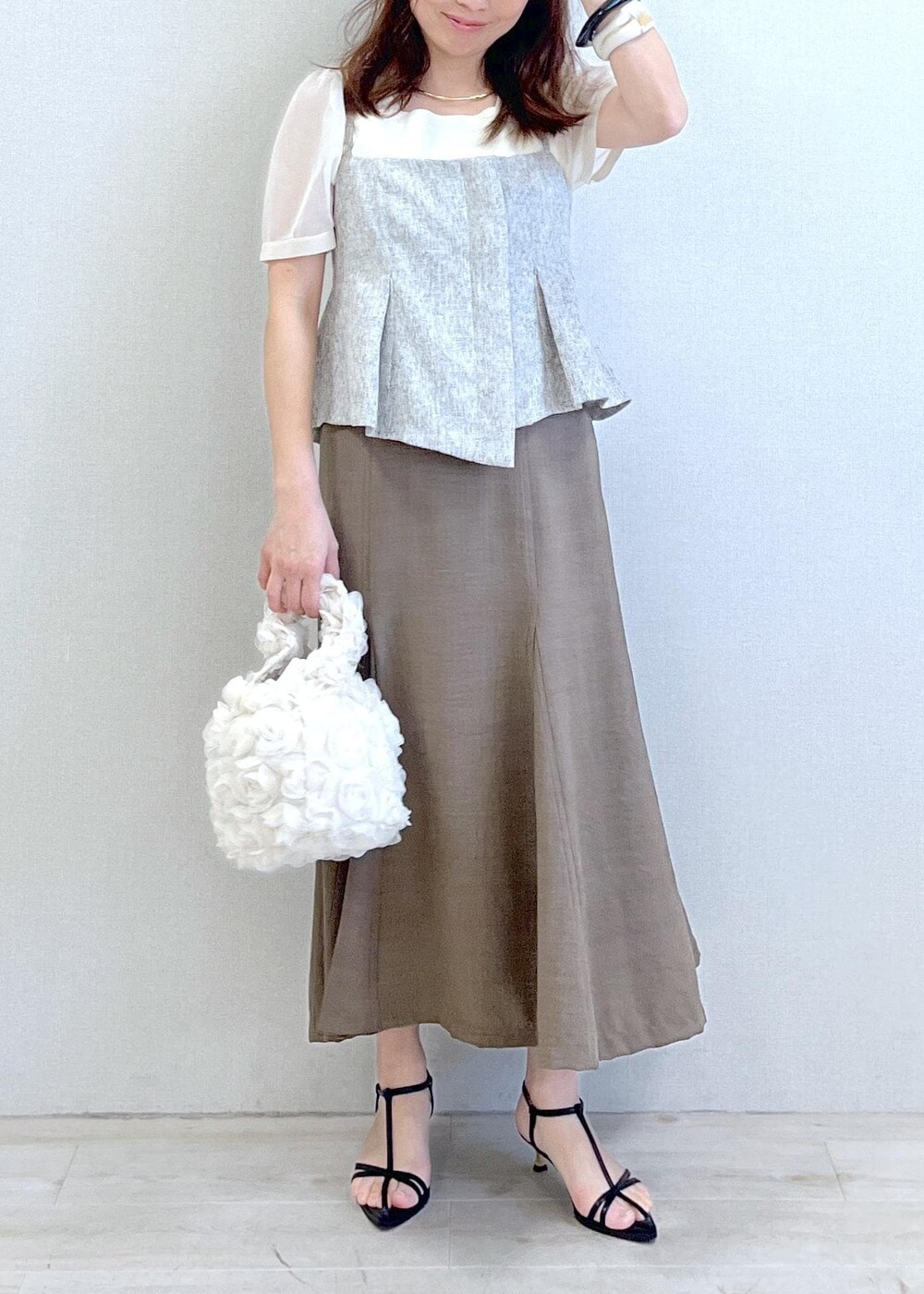 ブラック系のサンダル、ホワイト系のハンドバッグ、グリーン系のスカートを着用したレディースの春コーディネートの6枚目の写真