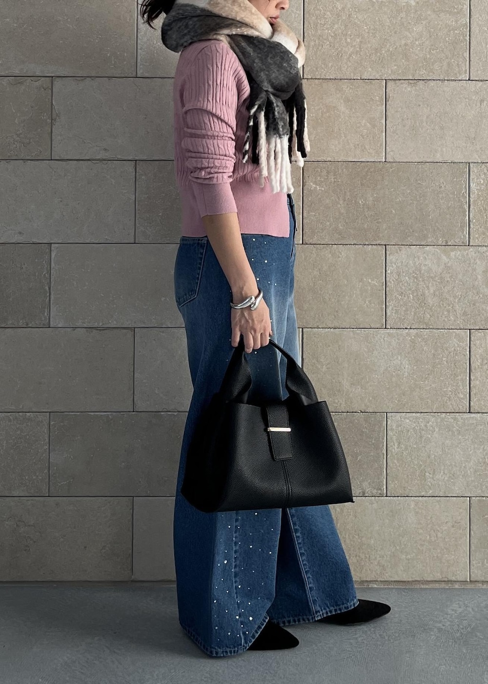 ブラック系のハンドバッグ、ピンク系のカーディガン/ボレロ、ブルー系のデニムパンツを着用したレディースの秋コーディネートの3枚目の写真