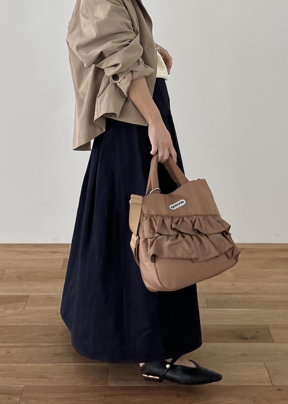 ブラック系のパンプス、ベージュ系のトートバッグ、ベージュ系のトレンチコートを着用したレディースの冬コーディネートの3枚目の写真