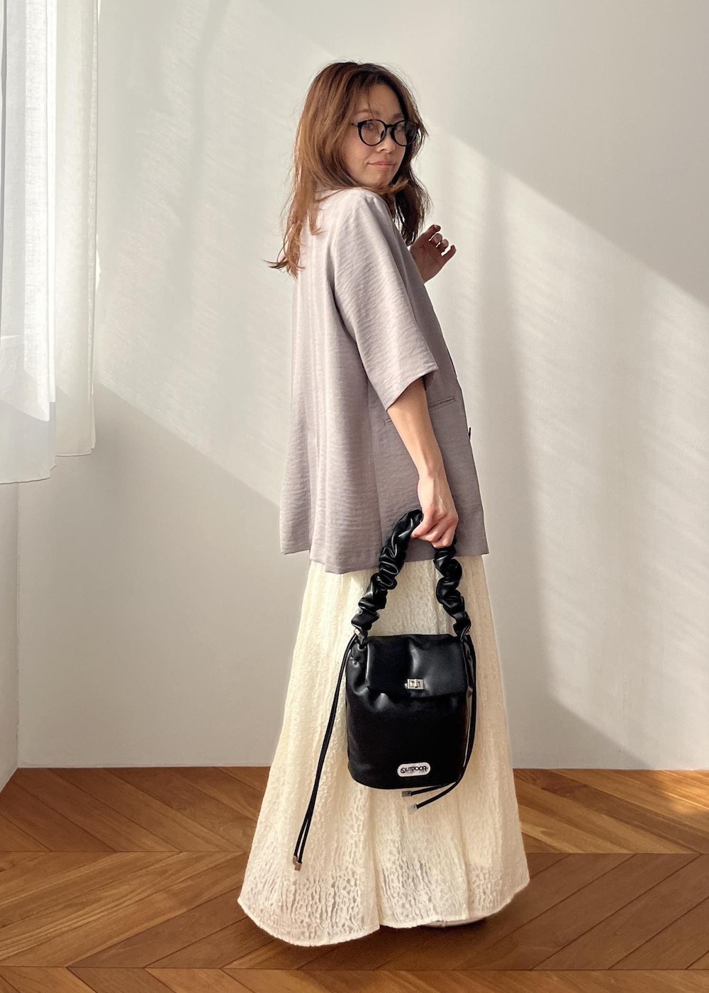 ホワイト系のスカート、ブラック系のショルダーバッグ、ホワイト系のサンダルを着用したレディースの春コーディネートの3枚目の写真