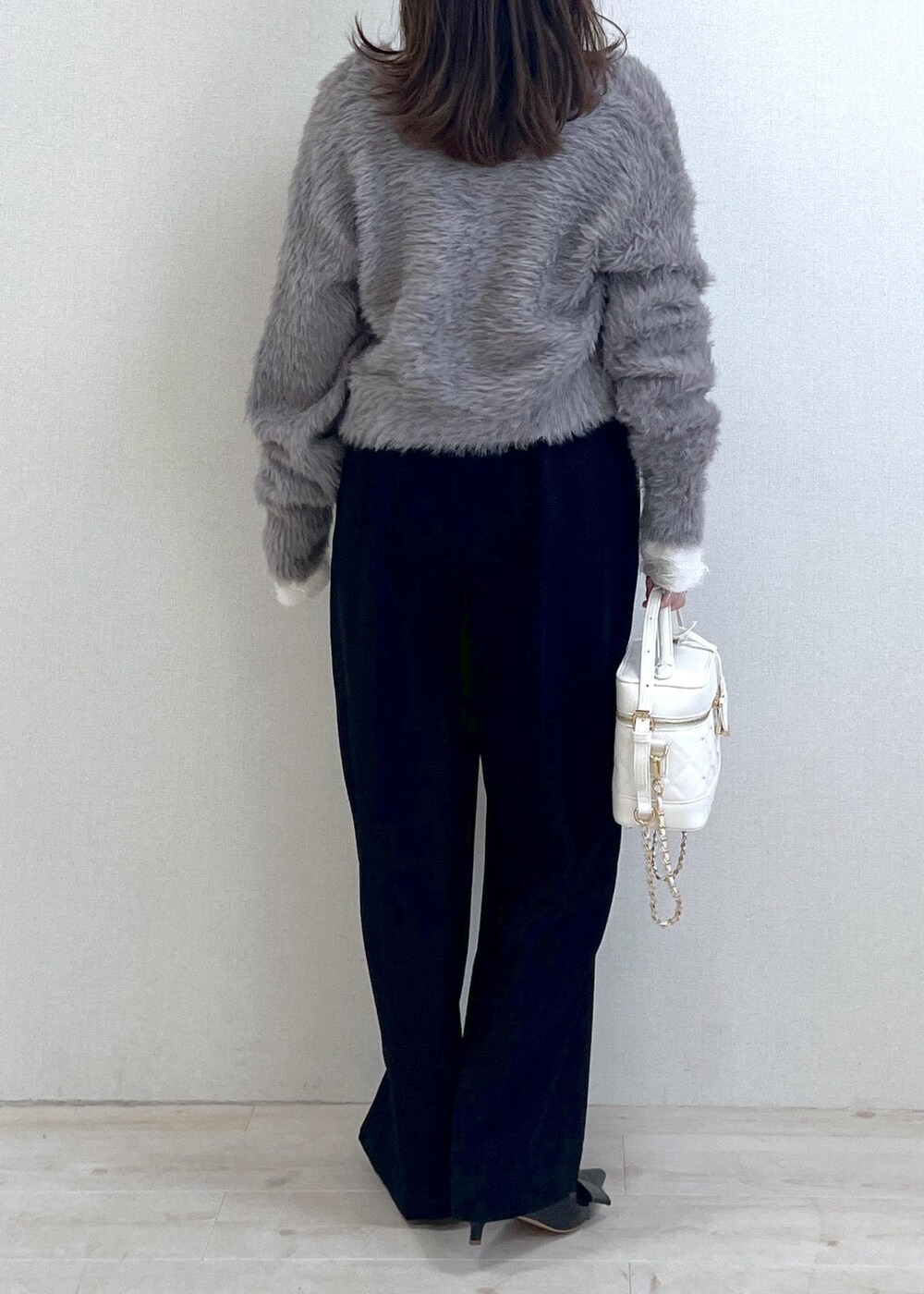 ブラック系のパンプス、ホワイト系のニット/セーター、グレー系のカーディガン/ボレロを着用したレディースの冬コーディネートの4枚目の写真