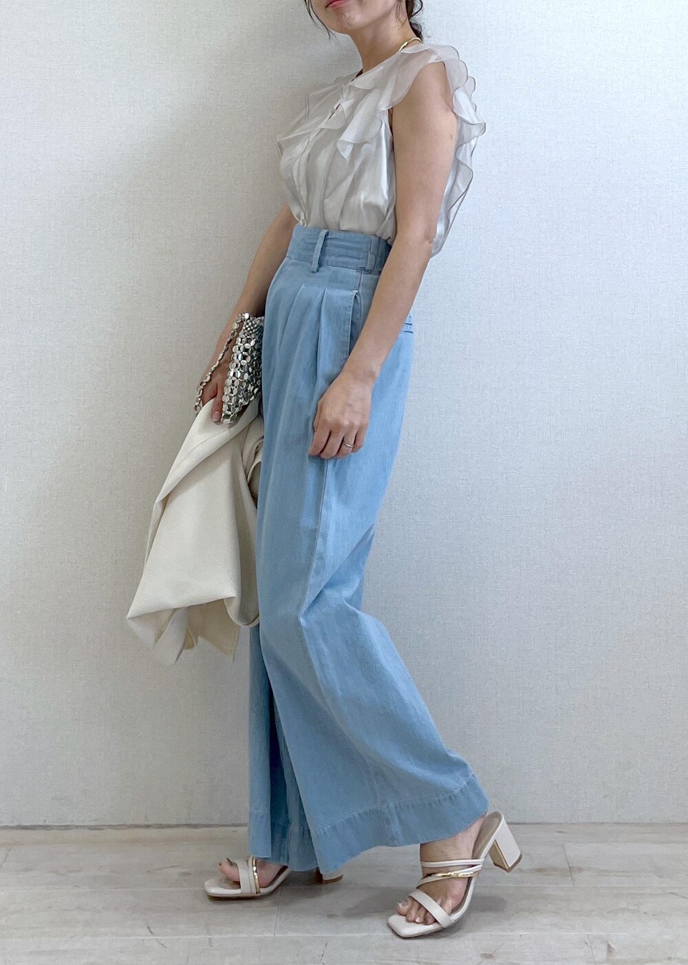 ホワイト系のサンダル、シルバー系のハンドバッグ、ブルー系のデニムパンツを着用したレディースの夏コーディネートの2枚目の写真