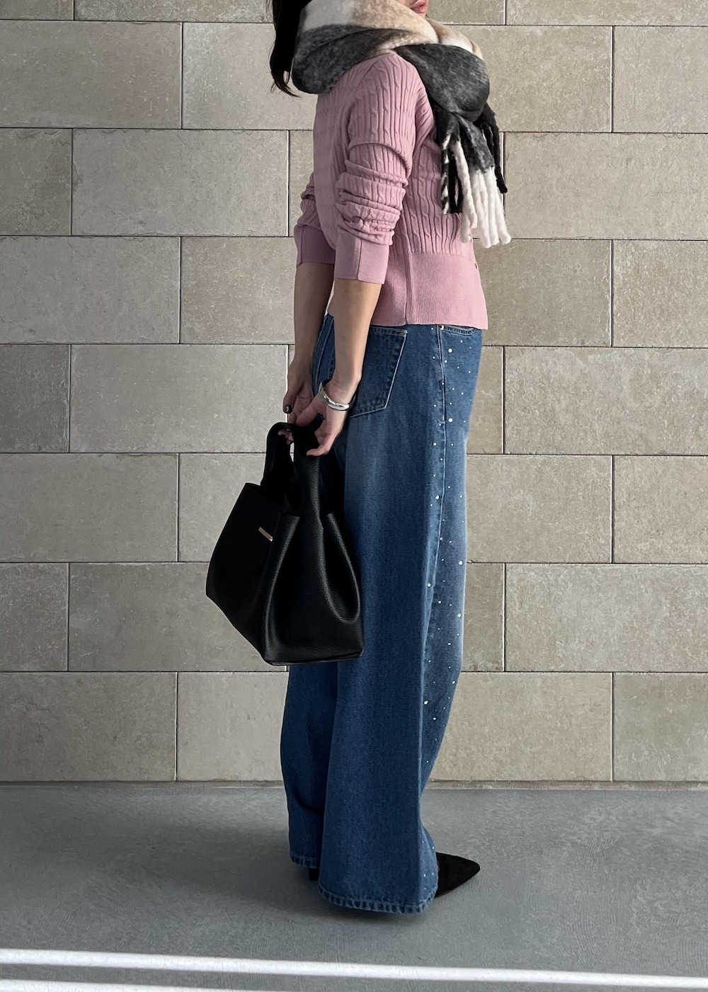 ブラック系のハンドバッグ、ピンク系のカーディガン/ボレロ、ブルー系のデニムパンツを着用したレディースの秋コーディネートの6枚目の写真