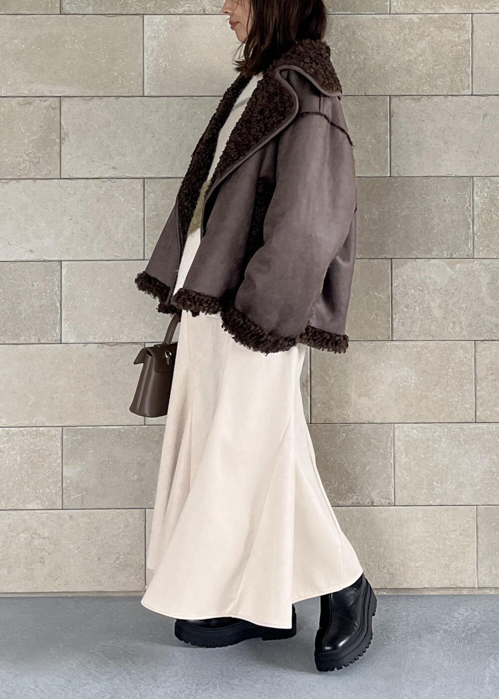 ベージュ系のショルダーバッグ、ブラック系のブーツ、ブラウン系のブルゾンを着用したレディースの秋コーディネートの2枚目の写真