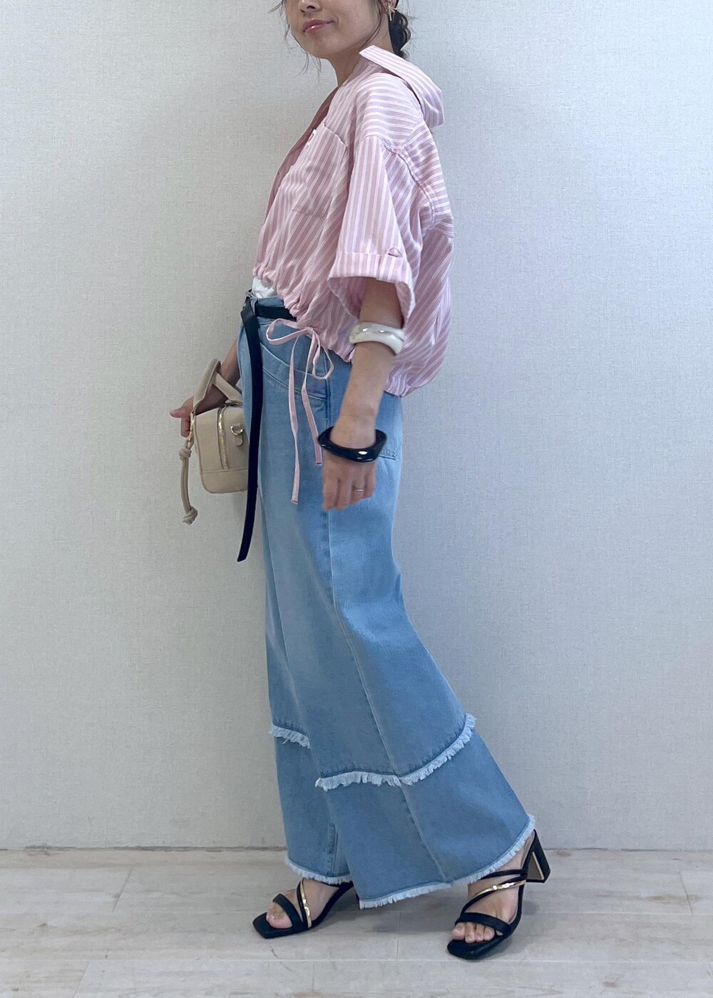 ブラック系のサンダル、ブルー系のデニムパンツ、ベージュ系のボストンバッグを着用したレディースの夏コーディネートの2枚目の写真