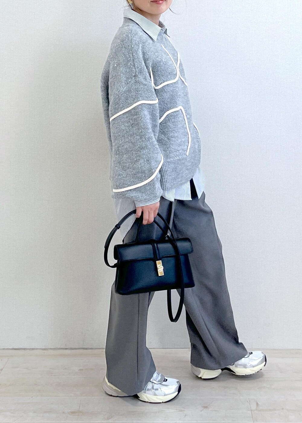 グレー系のニット/セーター、グレー系のスラックス、ブラック系のショルダーバッグを着用したレディースの冬コーディネートの3枚目の写真