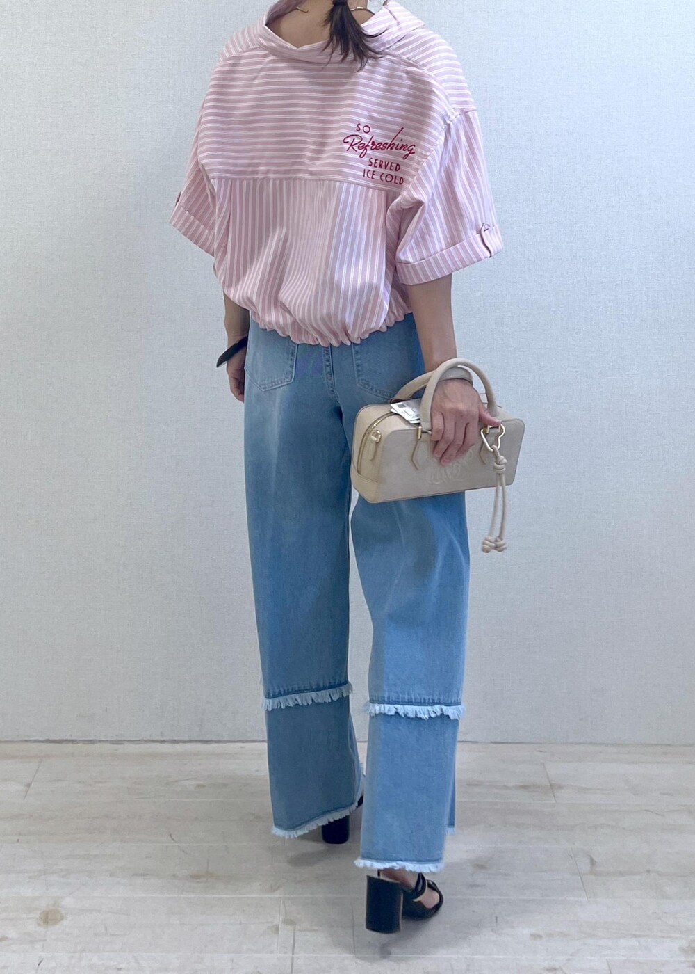 ブラック系のサンダル、ブルー系のデニムパンツ、ベージュ系のボストンバッグを着用したレディースの夏コーディネートの4枚目の写真