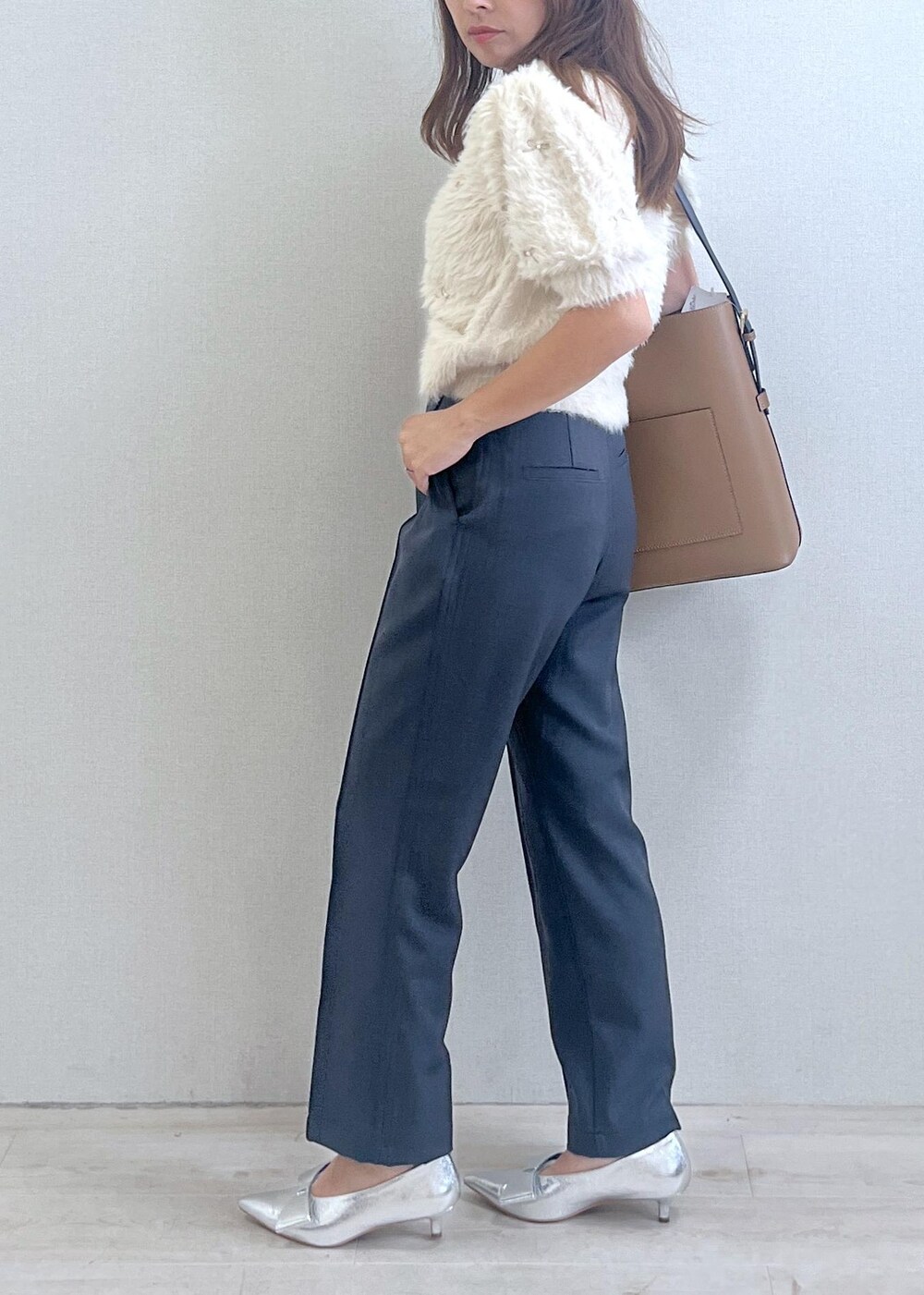 シルバー系のパンプス、イエロー系のショルダーバッグ、ホワイト系のニット/セーターを着用したレディースの秋コーディネートの2枚目の写真