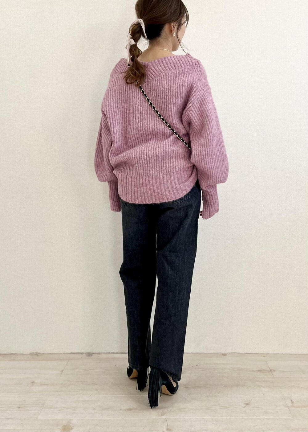 ブラック系のデニムパンツ、ブラック系のショルダーバッグ、ピンク系のニット/セーターを着用したレディースの冬コーディネートの3枚目の写真