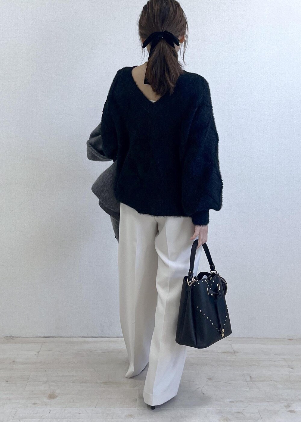 グレー系のブルゾン、ホワイト系のスラックス、ブラック系のニット/セーターを着用したレディースの冬コーディネートの9枚目の写真