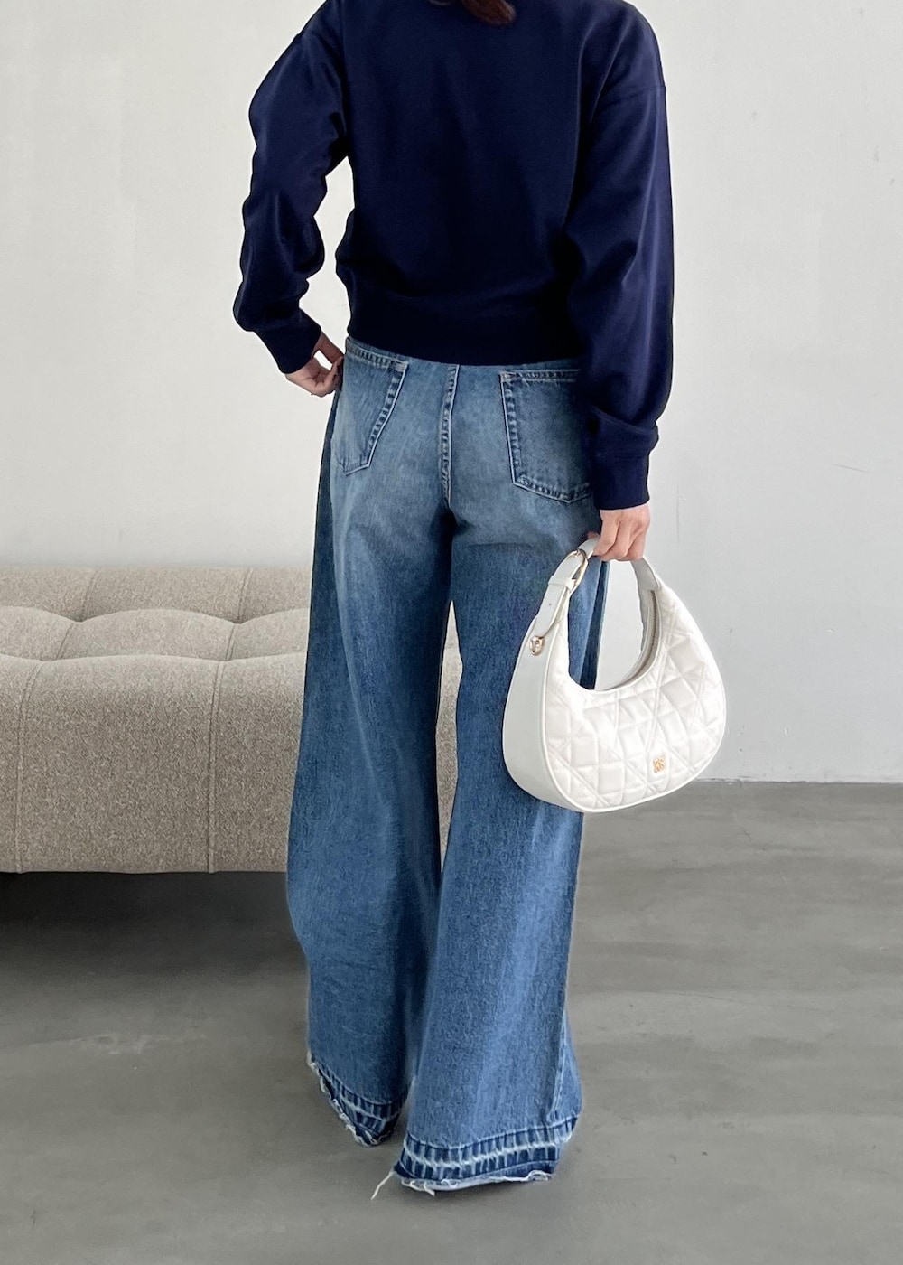 ホワイト系のハンドバッグ、ブラック系のパンプス、ブルー系のデニムパンツを着用したレディースの冬コーディネートの5枚目の写真