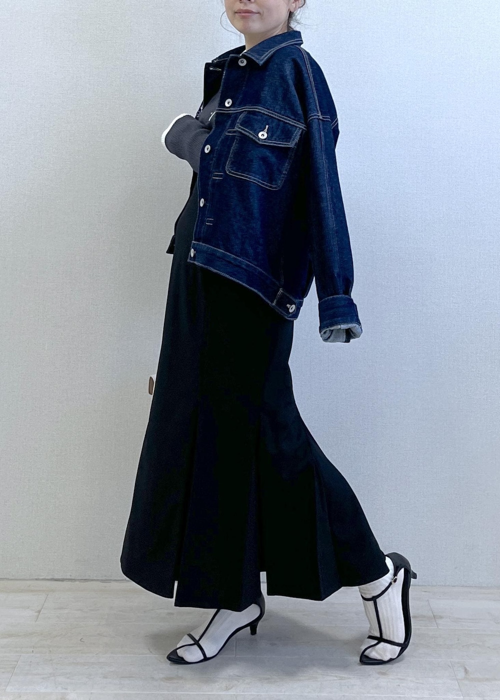 ブルー系のデニムジャケット、ブラック系のスカート、グレー系のニット/セーターを着用したレディースの冬コーディネートの2枚目の写真