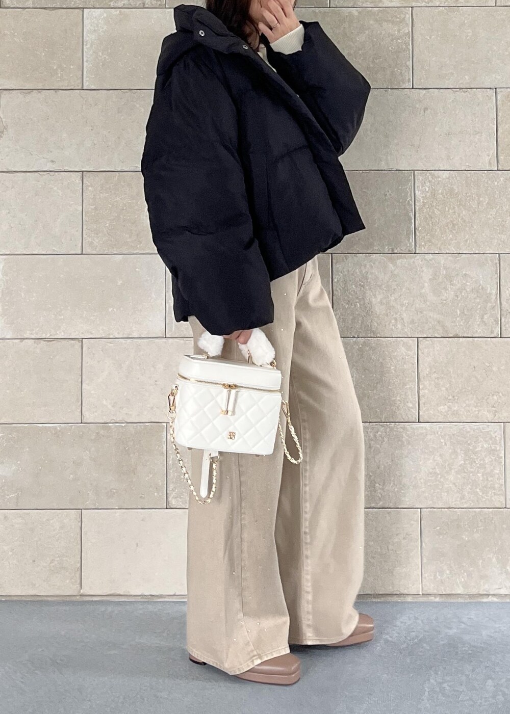 ブラック系のダウンジャケット/コート、ベージュ系のブーツ、ホワイト系のハンドバッグを着用したレディースの秋コーディネートの4枚目の写真