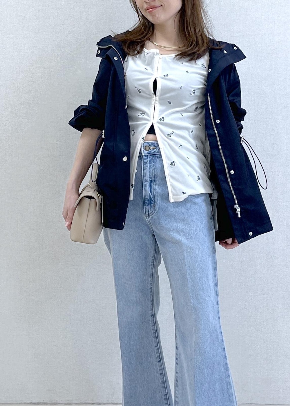 ベージュ系のショルダーバッグ、ブルー系のナイロンジャケット、ブラック系のキャミソールを着用したレディースの春コーディネートの5枚目の写真