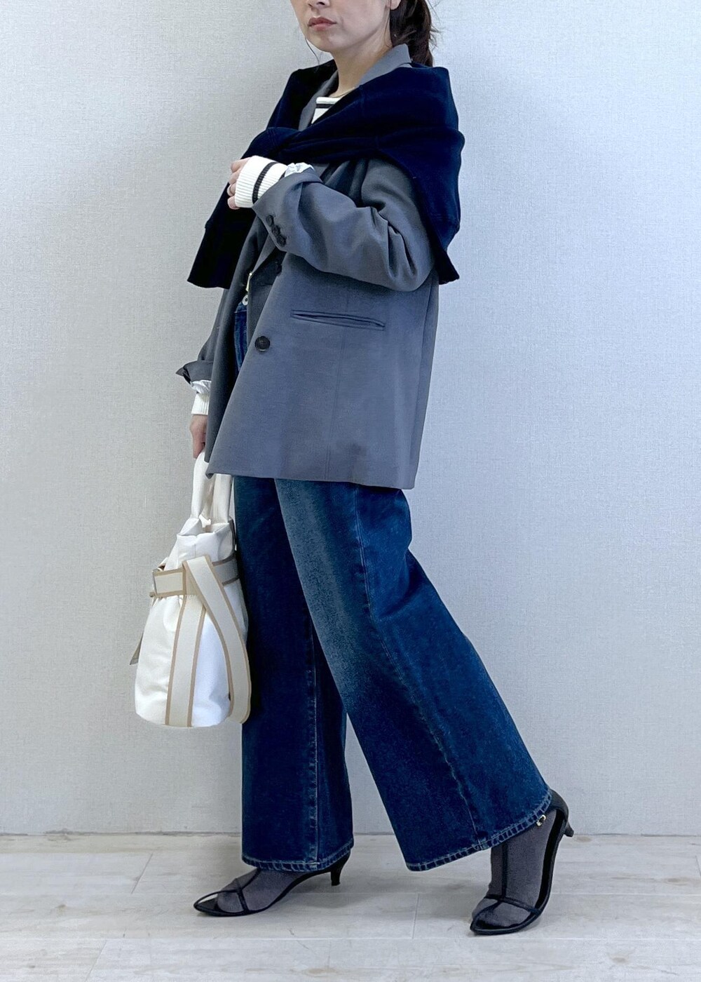 グレー系のテーラードジャケット、ブルー系のデニムパンツ、ホワイト系のニット/セーターを着用したレディースの冬コーディネートの6枚目の写真