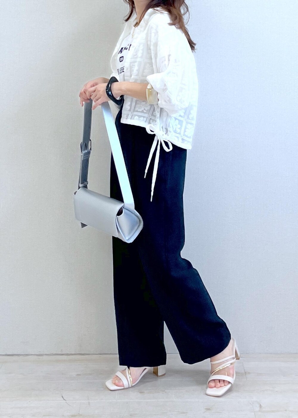 シルバー系のショルダーバッグ、ホワイト系のTシャツ/カットソー、ホワイト系のサンダルを着用したレディースの春コーディネートの3枚目の写真