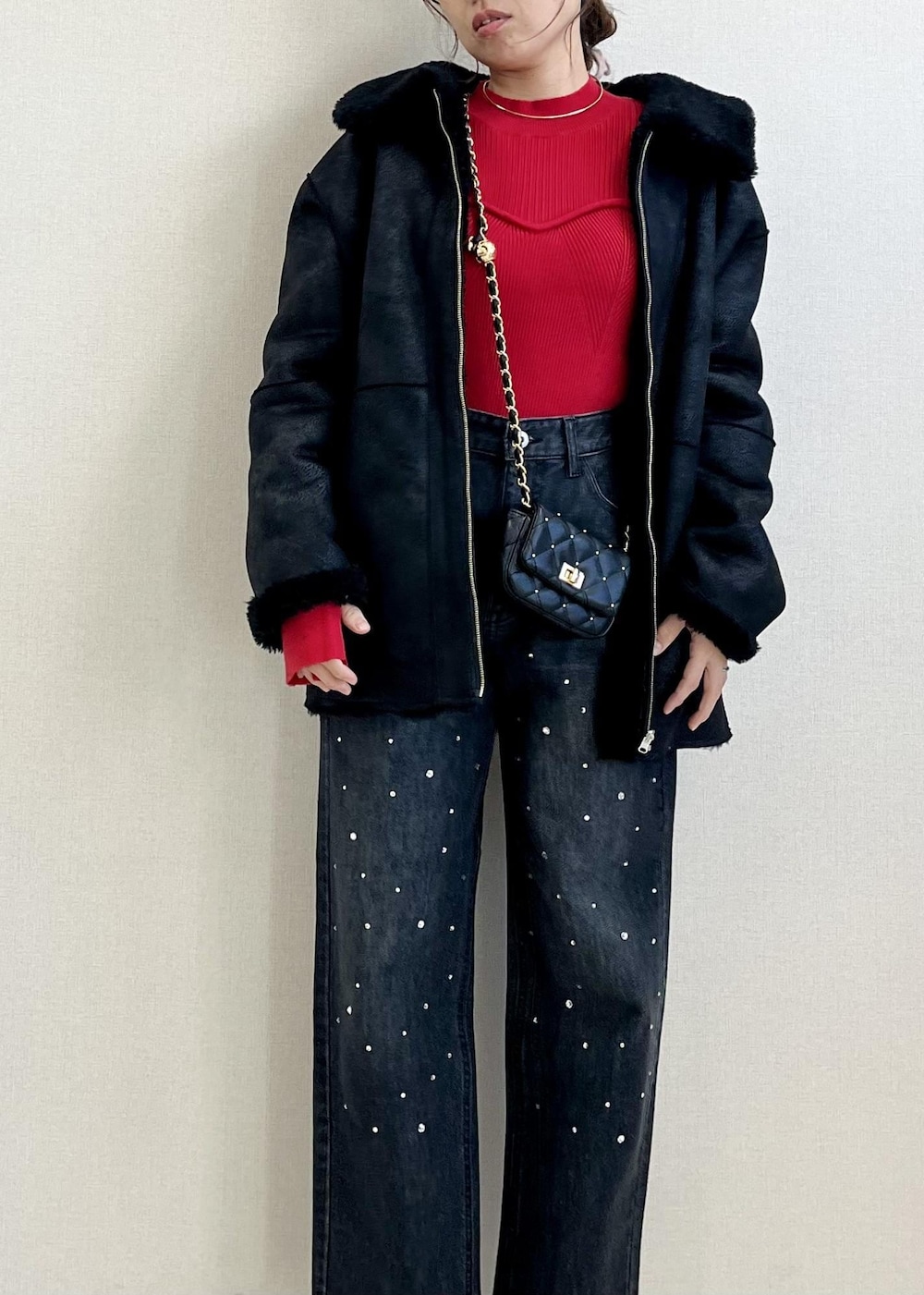 ブラック系のデニムパンツ、レッド系のニット/セーター、ブラック系のショルダーバッグを着用したレディースの冬コーディネートの3枚目の写真